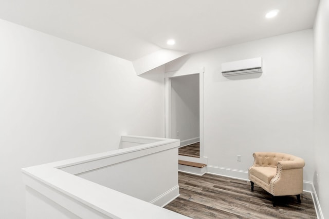 sitting room with dark wood-type flooring and a wall unit AC