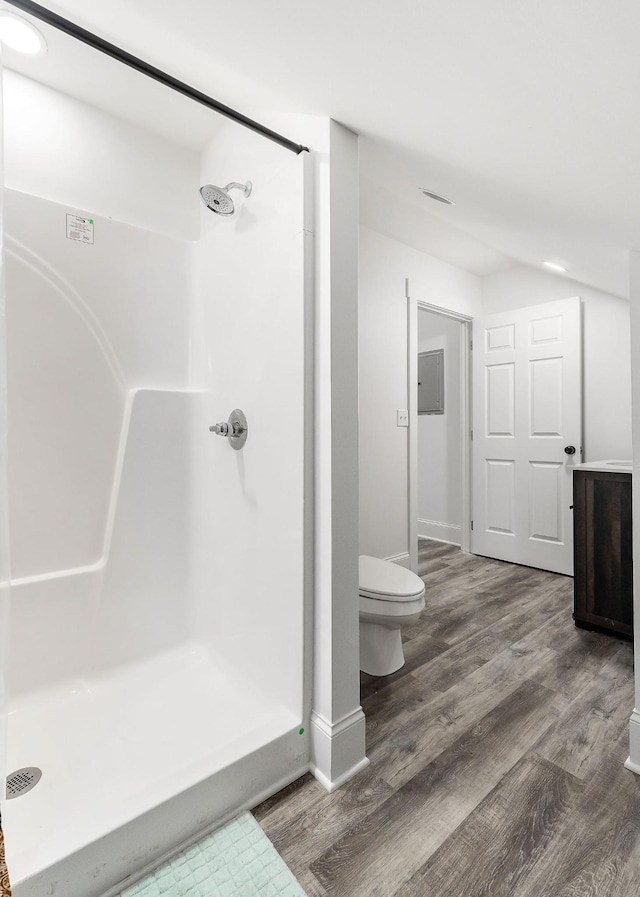 bathroom with hardwood / wood-style flooring, toilet, electric panel, and walk in shower