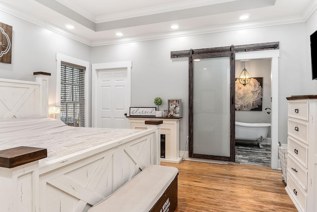 bedroom with a tray ceiling, crown molding, and light wood-type flooring