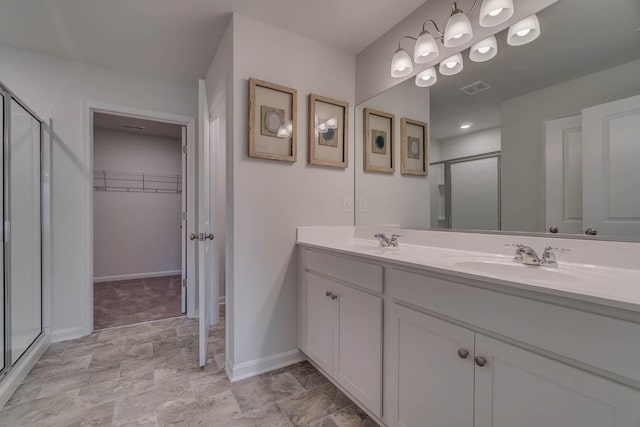 bathroom featuring a shower with door and vanity