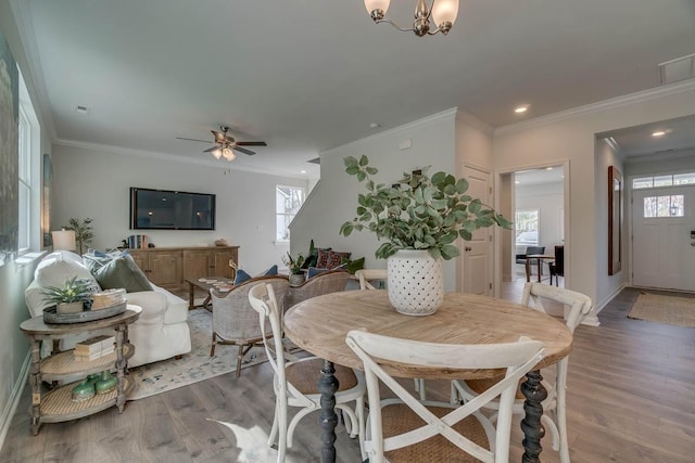 dining space with hardwood / wood-style flooring, ceiling fan with notable chandelier, and ornamental molding