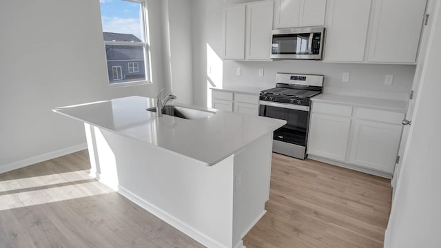 kitchen with stainless steel appliances, a center island with sink, and white cabinets