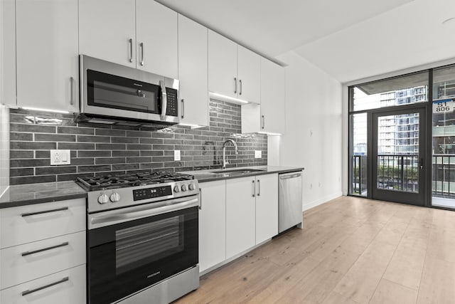 kitchen with tasteful backsplash, stainless steel appliances, sink, and white cabinets