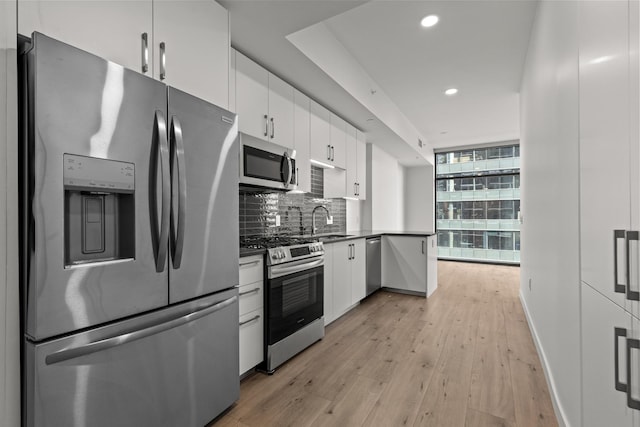 kitchen featuring tasteful backsplash, white cabinetry, sink, stainless steel appliances, and floor to ceiling windows