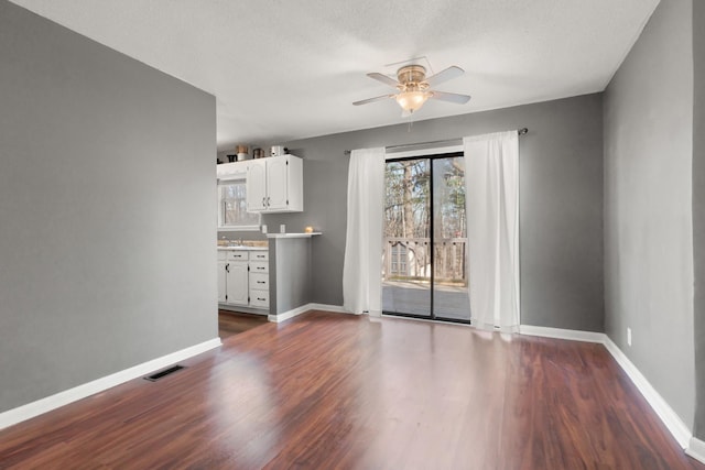 unfurnished living room featuring dark hardwood / wood-style flooring, sink, a textured ceiling, and ceiling fan