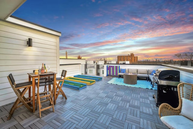 patio terrace at dusk featuring grilling area and an outdoor living space