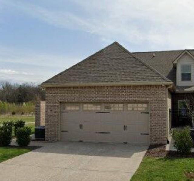 view of property exterior featuring a garage, brick siding, and driveway