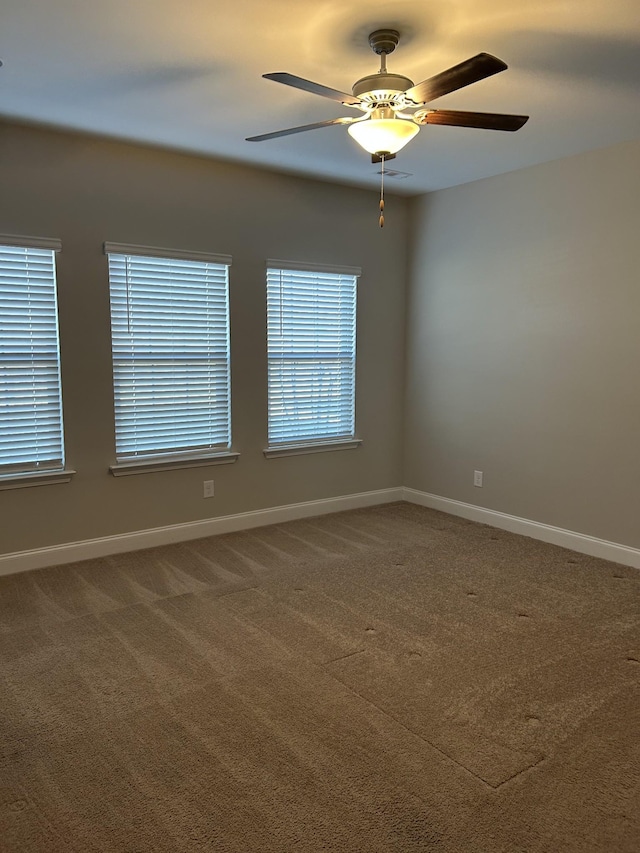 carpeted spare room featuring baseboards and a ceiling fan