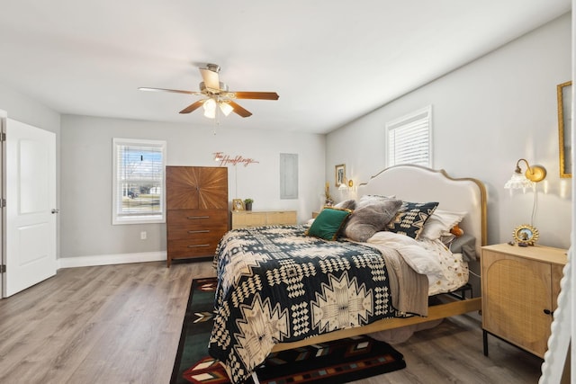 bedroom featuring ceiling fan, hardwood / wood-style floors, and multiple windows