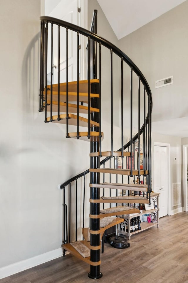 stairway with vaulted ceiling and hardwood / wood-style floors