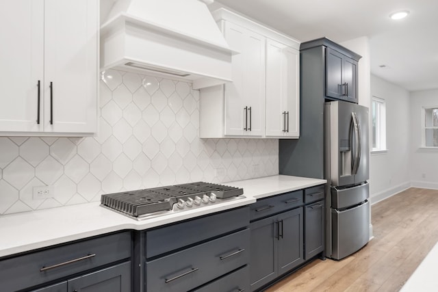 kitchen with custom exhaust hood, gray cabinetry, white cabinetry, stainless steel appliances, and decorative backsplash