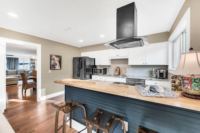 kitchen featuring white cabinetry, sink, island exhaust hood, stainless steel appliances, and dark wood-type flooring