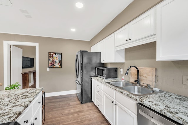 kitchen with light stone counters, stainless steel appliances, sink, and white cabinets