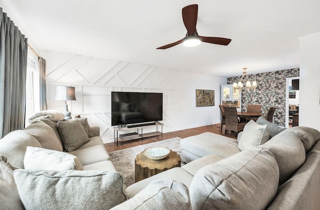 living room with dark hardwood / wood-style flooring and ceiling fan with notable chandelier