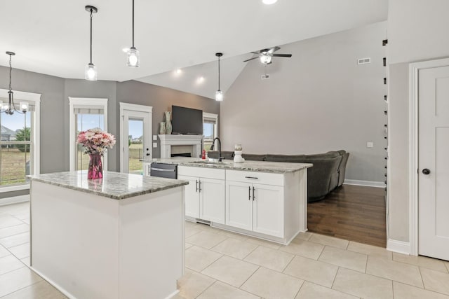 kitchen with white cabinetry, decorative light fixtures, stainless steel dishwasher, a kitchen island, and light stone countertops