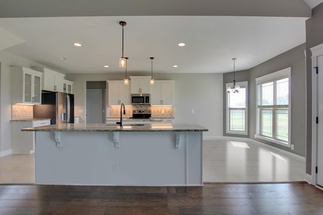 kitchen featuring a kitchen bar, sink, pendant lighting, stainless steel appliances, and a large island