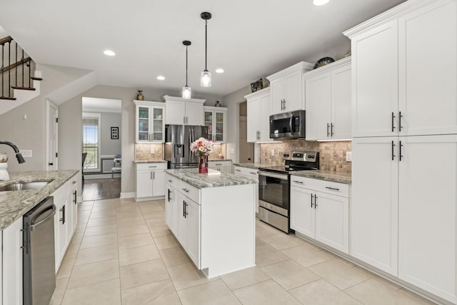 kitchen with sink, a center island, stainless steel appliances, light stone countertops, and white cabinets