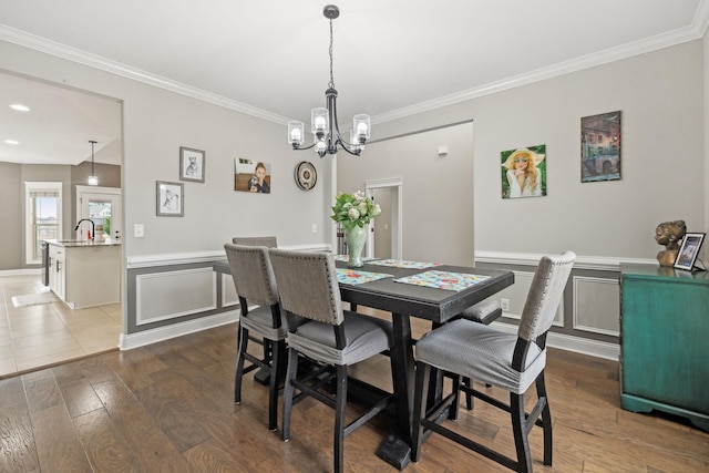 dining area featuring sink, crown molding, dark wood-type flooring, and a notable chandelier