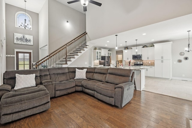 living room featuring ceiling fan with notable chandelier, sink, hardwood / wood-style floors, and a high ceiling