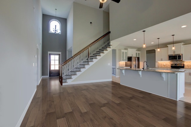 kitchen featuring appliances with stainless steel finishes, a breakfast bar, decorative light fixtures, white cabinets, and dark hardwood / wood-style flooring