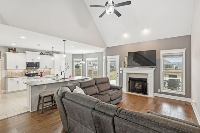 living room with high vaulted ceiling, sink, dark wood-type flooring, and a fireplace