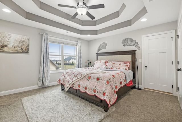 bedroom with a tray ceiling, ceiling fan, and carpet flooring