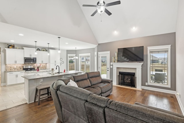 living room with dark hardwood / wood-style flooring, sink, a fireplace, and high vaulted ceiling