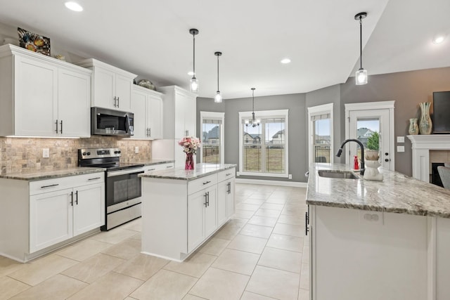 kitchen featuring white cabinetry, stainless steel appliances, sink, and an island with sink