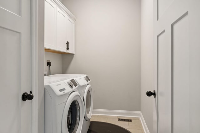 clothes washing area with cabinets, tile patterned flooring, and washing machine and dryer