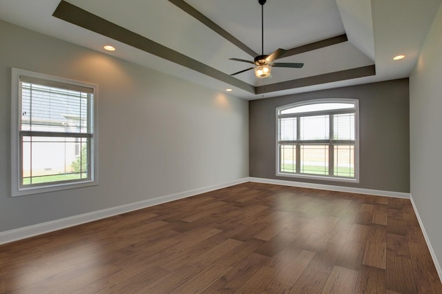 empty room with dark hardwood / wood-style flooring, a tray ceiling, and ceiling fan