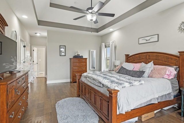 bedroom with ceiling fan, dark hardwood / wood-style flooring, and a raised ceiling