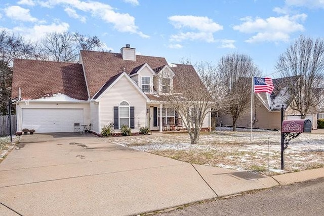 new england style home with concrete driveway, a chimney, and an attached garage