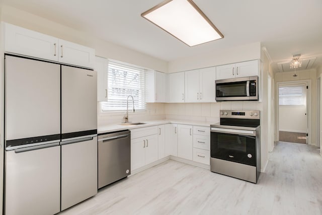 kitchen featuring stainless steel appliances, sink, light hardwood / wood-style flooring, and white cabinets