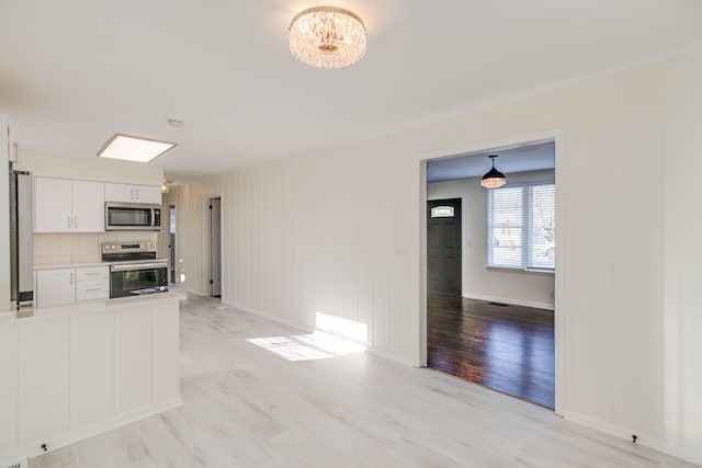 interior space with white cabinetry, light wood-type flooring, and appliances with stainless steel finishes