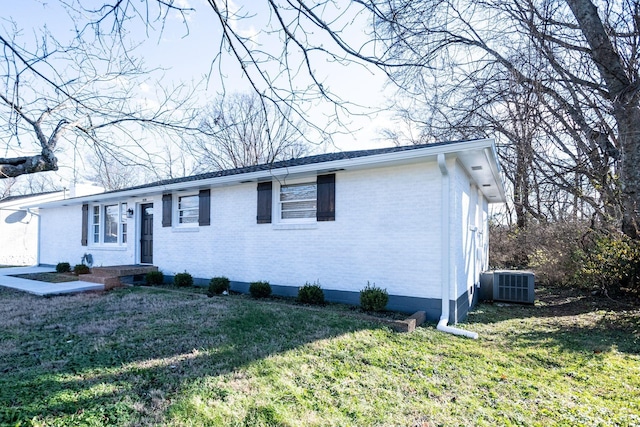 ranch-style house with a front yard and central AC unit