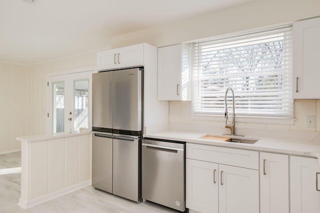 kitchen with stainless steel appliances, white cabinetry, sink, and a wealth of natural light