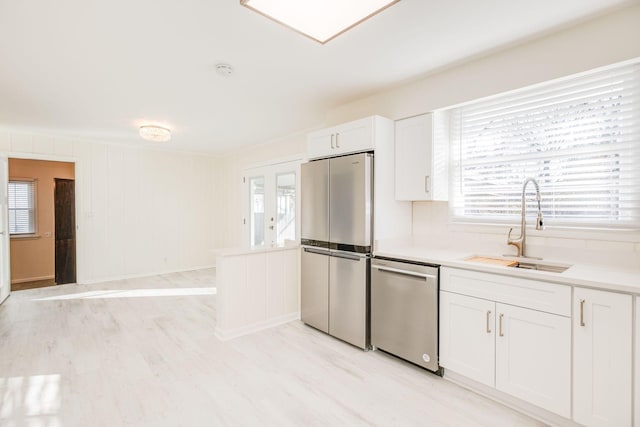 kitchen featuring appliances with stainless steel finishes, sink, a wealth of natural light, and white cabinets