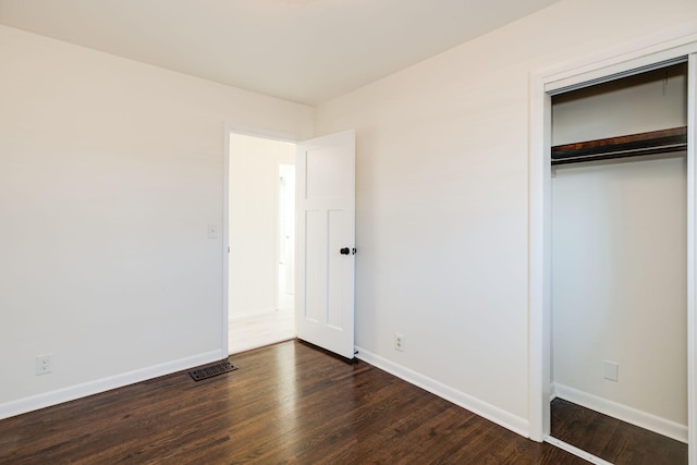 unfurnished bedroom with dark wood-type flooring and a closet