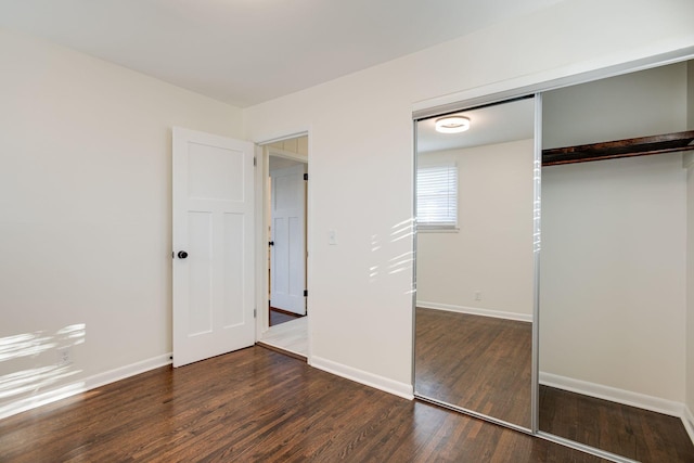 unfurnished bedroom with dark hardwood / wood-style floors and a closet