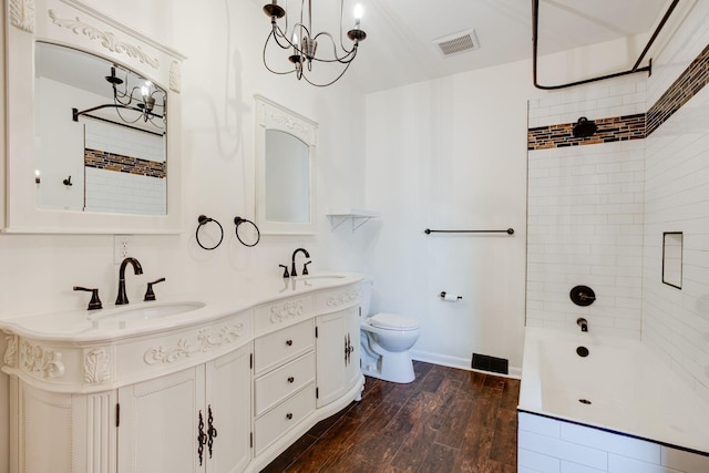 full bathroom featuring wood-type flooring, tiled shower / bath, vanity, and toilet