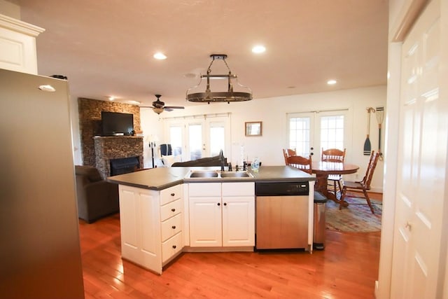 kitchen with a fireplace, white cabinetry, sink, stainless steel dishwasher, and french doors