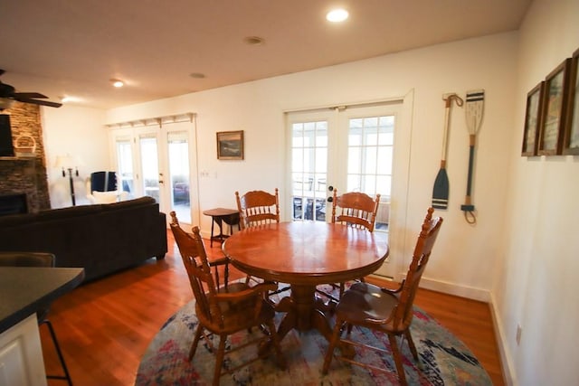 dining area with dark hardwood / wood-style flooring, a stone fireplace, plenty of natural light, and french doors