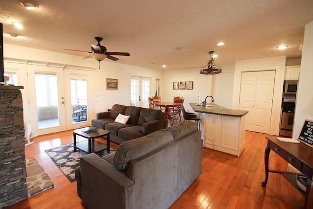 living room with sink, light hardwood / wood-style floors, french doors, and ceiling fan