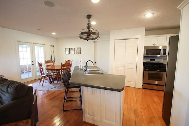 kitchen with french doors, sink, white cabinetry, appliances with stainless steel finishes, and hardwood / wood-style floors