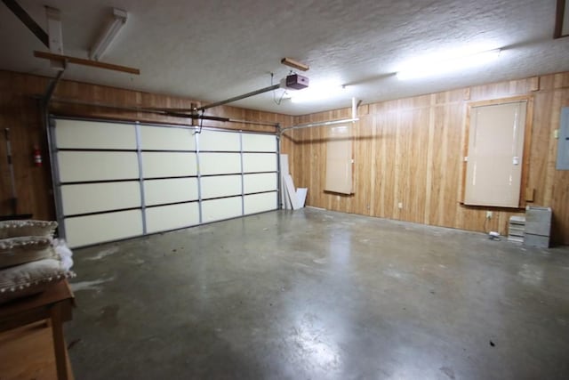 garage featuring a garage door opener, electric panel, and wood walls