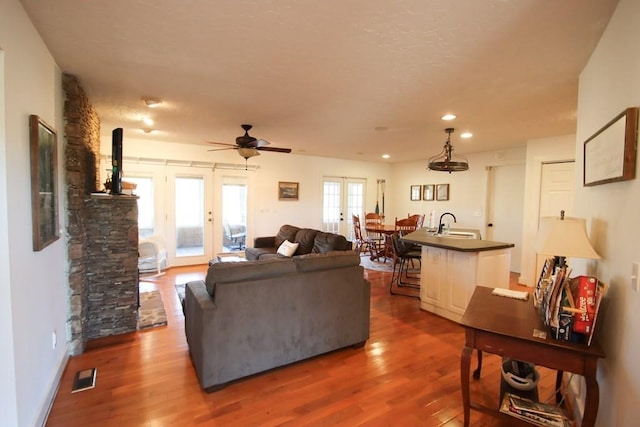 living room with dark wood-type flooring, french doors, and ceiling fan