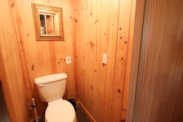 bathroom with toilet and wood walls