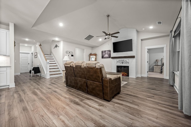 living room with ceiling fan, lofted ceiling, light wood-type flooring, and a fireplace