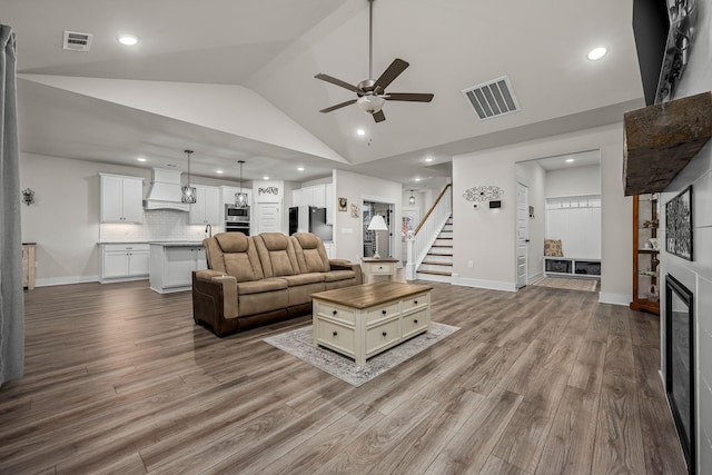 living room with ceiling fan, high vaulted ceiling, and light hardwood / wood-style floors