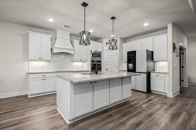 kitchen featuring stainless steel appliances, premium range hood, a kitchen island with sink, and white cabinets